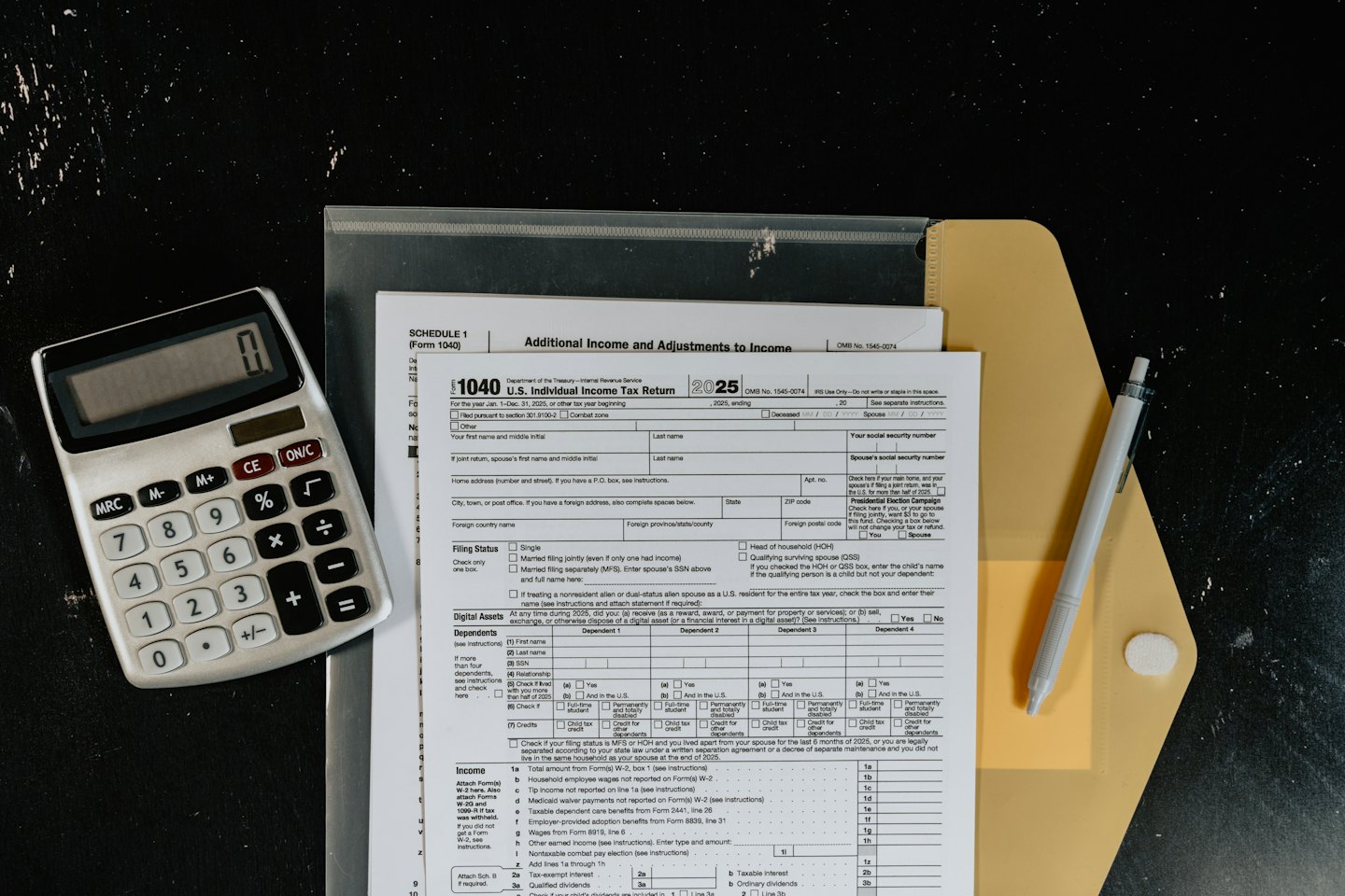 Moduli fiscali statunitensi, calcolatrice e penna su una scrivania.