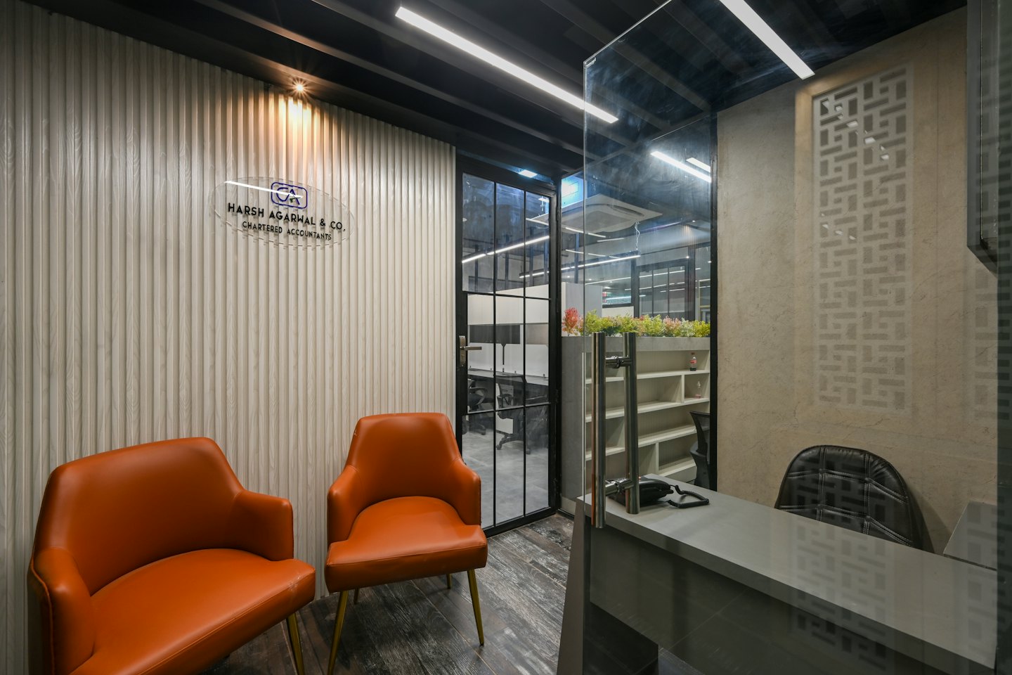 Reception moderna dell'ufficio con sedie arancioni e scrivania grigia.